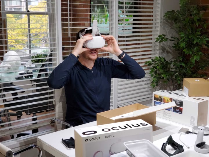 Lorne Fade at his desk trying on an Oculus Quest 2 headset, with headset boxes in front of him.